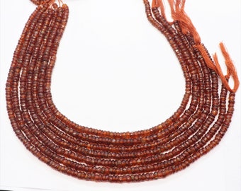 May include: A strand of brown gemstone beads, with multiple strands of beads arranged in a U-shape. The beads are small and round, with a slightly faceted appearance.