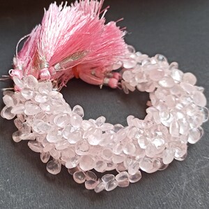 Puede incluir: Una hebra de cuentas de piedra preciosa de cuarzo rosa pálido, con un borla rosa en el extremo. Las cuentas tienen una forma irregular y un acabado natural y pulido.