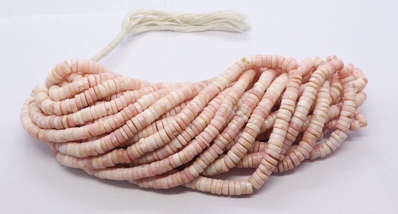 Pode incluir: Um fio de contas rosa e brancas em forma de disco. As contas s&atilde;o de uma cor pastel suave e parecem ser feitas de um material natural. As contas s&atilde;o enfiadas com um cord&atilde;o branco e s&atilde;o adequadas para a fabrica&ccedil;&atilde;o de joias.