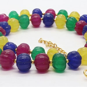 May include: A multi-colored beaded necklace with a gold clasp. The beads are carved in a pumpkin shape and are yellow, green, pink, and blue.