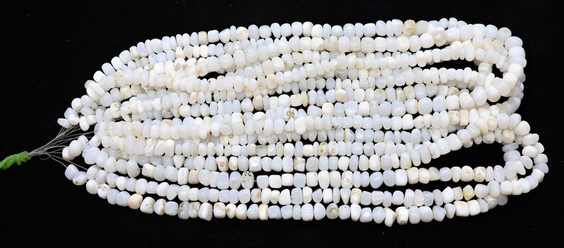 May include: A strand of white gemstone beads, each bead is a unique, irregular shape. The beads are strung on a thin wire and are ready to be used for jewelry making.