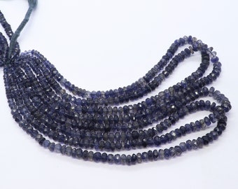 May include: Strands of faceted, dark blue gemstone beads. The beads are strung together, with a dark green tassel at the top. The beads have a subtle sparkle and are arranged in a cascading pattern.