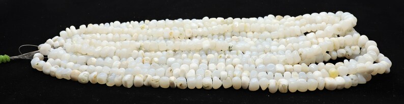 May include: A strand of white opaque gemstone beads. The beads are irregular in shape and have a slightly cloudy appearance.