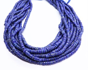 Pode incluir: Um fio de contas de lapis-lazúli azul escuro, cada conta é facetada e tem um formato ligeiramente irregular. As contas são enfiadas em um cordão fino e estão dispostas em um padrão solto e fluido.