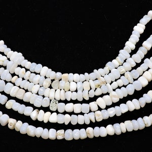 May include: A strand of white gemstone beads, with a slightly irregular, pebble-like shape. The beads are strung on a thin wire and are arranged in a loose, flowing pattern.