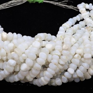 May include: A strand of white gemstone beads, each bead is a smooth, irregular oval shape. The beads are strung on a silver wire.