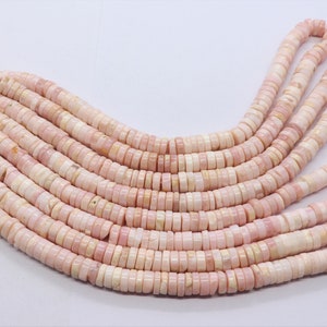 Pode incluir: Fios de contas de pedras preciosas rosa e creme. As contas s&atilde;o planas, em forma de disco e enfiadas. As contas t&ecirc;m uma apar&ecirc;ncia natural e org&acirc;nica, com varia&ccedil;&otilde;es de cor e textura. As contas s&atilde;o provavelmente usadas para fazer joias.