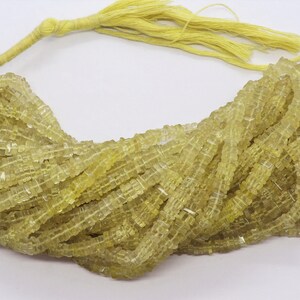 May include: A strand of light yellow gemstone beads, each bead is a square shape with a faceted finish. The beads are strung on a thin thread and are ready to be used for jewelry making.
