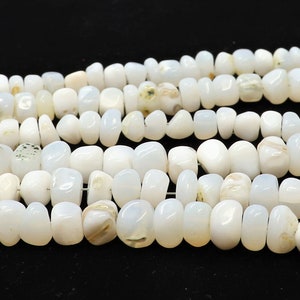 May include: A strand of white opaque gemstone beads, each bead is a slightly irregular oval shape.