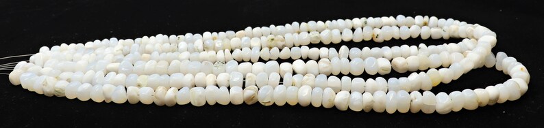 May include: A strand of white opaque gemstone beads, each bead is a slightly irregular oval shape.