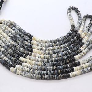 May include: A necklace composed of multiple strands of small, round beads. The beads are primarily white, gray, and black, creating a marbled effect. The necklace is arranged in a curved shape, showcasing the color variations.