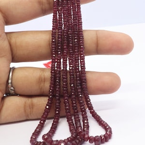 May include: A strand of deep red ruby beads, faceted and polished, strung together to form a necklace. The beads are small and uniform in size, creating a delicate and elegant look.