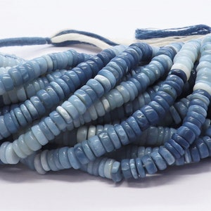 May include: A strand of blue and white opal beads. The beads are small and round, and they are strung on a white thread. The beads are a mix of light and dark blue, and they have a slightly iridescent sheen.