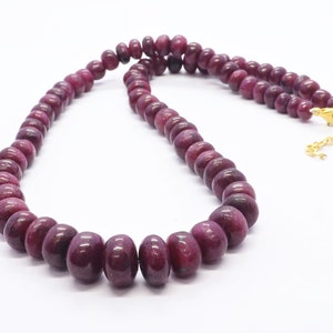 Puede incluir: Un collar hecho de cuentas de rubí rojo oscuro con un cierre de oro.