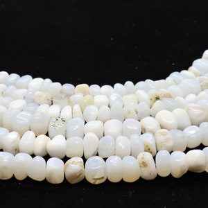 May include: A strand of white gemstone beads, likely moonstone, with a slightly irregular, rounded shape. The beads are strung on a thin wire and are arranged in a loose, flowing pattern.