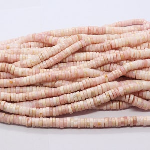 Pode incluir: Um conjunto de contas planas e redondas rosa e creme, enfiadas juntas. As contas s&atilde;o uniformes em tamanho e forma, com uma superf&iacute;cie ligeiramente irregular. As contas s&atilde;o provavelmente feitas de um material natural, como pedra ou concha.
