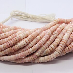 Pode incluir: Um fio de contas planas e redondas rosa e brancas. As contas s&atilde;o em forma de disco e parecem ser feitas de um material natural. As contas s&atilde;o enfiadas com um cord&atilde;o branco. As contas t&ecirc;m aproximadamente 0,6 cm de di&acirc;metro.