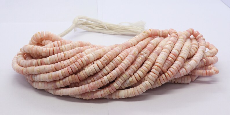 Pode incluir: Um fio de contas planas e redondas rosa e brancas. As contas s&atilde;o em forma de disco e parecem ser feitas de um material natural. As contas s&atilde;o enfiadas com um cord&atilde;o branco. As contas t&ecirc;m aproximadamente 0,6 cm de di&acirc;metro.
