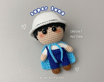 May include: Crochet pattern for a super tuna amigurumi doll. The doll is wearing a white hat, a blue and white shirt, and blue overalls. The doll has black hair and brown eyes.