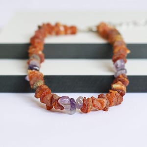 May include: A necklace made of amber and amethyst beads. The amber beads are a warm brown color, and the amethyst beads are a light purple color.