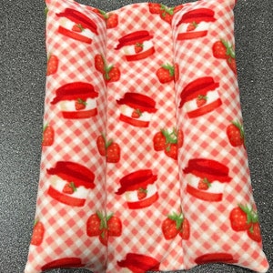 May include: A red and white gingham fabric heating pad with a strawberry pattern. The pad is divided into three sections.