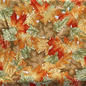 May include: A fabric pattern featuring a dense arrangement of autumn leaves. The leaves display a variety of colors, including shades of red, orange, yellow, green, and brown. The design evokes a fall theme, with a mix of maple and other leaf types.