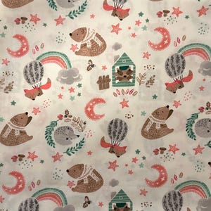 May include: White fabric with a repeating pattern of woodland creatures and celestial elements. Bears, foxes in hot air balloons, hedgehogs, rainbows, moons, and stars in shades of brown, pink, green, and gray are featured.