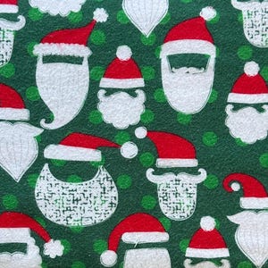 May include: A festive pattern featuring Santa hats and beards in white and red against a green background with green polka dots. The design is repeated across the surface, creating a holiday-themed textile.