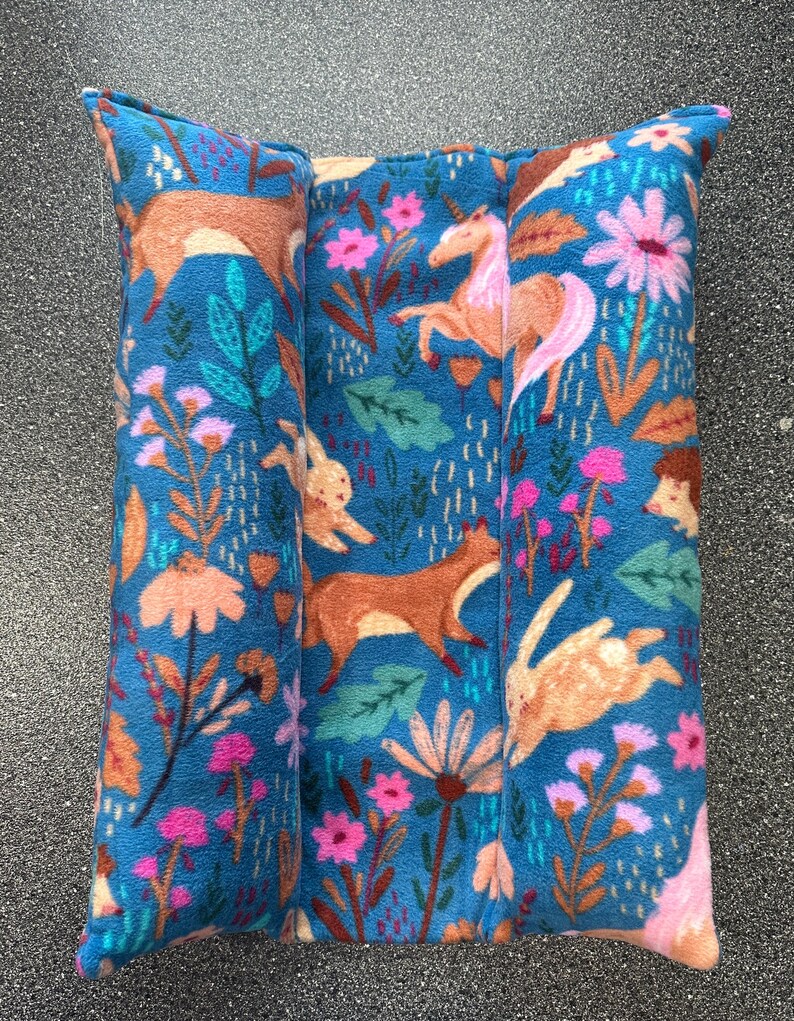 May include: A blue fabric cushion with a woodland animal print. The print features a fox, a rabbit, a deer, a unicorn, and a hedgehog. The cushion is made of soft, plush fabric and is perfect for adding a touch of whimsy to any room.