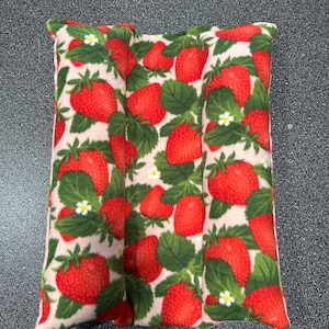 May include: A pink and white fabric pillow with a strawberry print. The pillow is divided into three sections and is filled with a soft material.