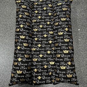 May include: Three black and gold decorative pillows with the text "Queen Bee" repeated in a pattern. Each pillow features a gold crown and bee design.