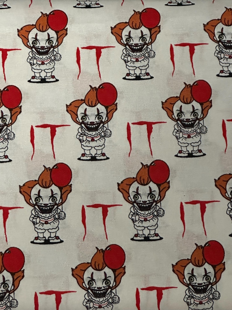K&ouml;nnte beinhalten: Wei&szlig;er Stoff mit einem sich wiederholenden Muster eines Pennywise-Cartoons aus dem Film ES. Pennywise h&auml;lt einen roten Ballon und hat ein bedrohliches L&auml;cheln. Die Worte "ES" sind in Rot auf den Stoff gedruckt.
