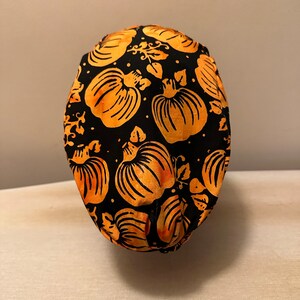 May include: Black fabric face mask with an orange pumpkin pattern.