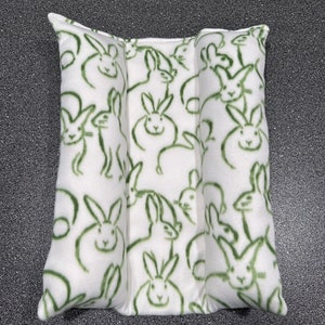 May include: A white pillow with a green bunny rabbit pattern. The pillow is divided into three sections.