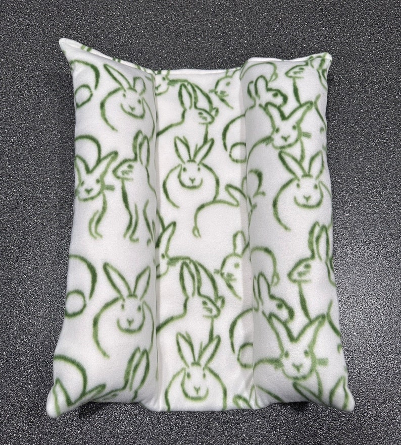 May include: A white pillow with a green bunny rabbit pattern. The pillow is divided into three sections.