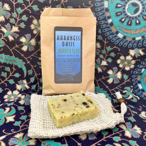 Puede incluir: Una pastilla de jabón artesanal elaborado en frío en una bolsa de papel marrón. El jabón está etiquetado como "Harkness Oasis Juniper Lime" y pesa 2 oz. Los ingredientes son: agua, aceite de oliva y coco saponificados, hojas y bayas de enebro, aceite esencial de lima, aceite esencial de cedro.