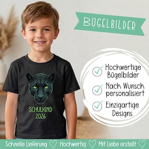 Könnte beinhalten: Ein schwarzes T-Shirt mit kurzen Ärmeln und einem Grafikdruck eines schwarzen Panthers mit leuchtend grünen Augen. Unter dem Panther steht der grüne Schriftzug SCHULKIND 2026. Das Bild enthält deutsche Textüberlagerungen zu Bügelbildern.