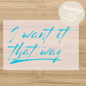 Puede incluir: Una transferencia termoadhesiva de color azul claro con el texto manuscrito I want it That way. El diseño incluye una insignia circular en la esquina superior derecha con el texto Bügelbild y un dibujo lineal de una plancha, indicando su uso.