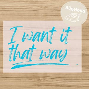 Könnte beinhalten: Eine hellrosa Bügelfolie mit dem leuchtend cyanfarbenen Schriftzug I want it that way in einer handschriftlichen Schriftart, unterstrichen durch eine horizontale Linie. Ein runder beiger Aufkleber oben rechts zeigt den Text Bügelbild.