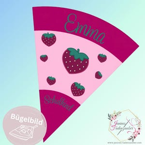 Peut inclure: Un écusson thermocollant rose et magenta avec un motif de fraise et le nom "Emma" en écriture verte. L'écusson comporte également le mot "Schulkind" et un petit logo rond avec une icône de fer à repasser.
