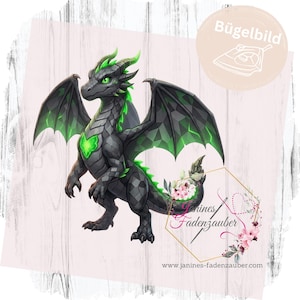 Könnte beinhalten: Ein Bügelbild mit einem schwarzen Drachen mit geometrischen Schuppen, leuchtend grünen Akzenten an Flügeln, Brust und Rücken sowie leuchtend grünen Augen. Das Design enthält ein kreisförmiges Logo mit dem Text Bügelbild und Janines Fadenzauber.