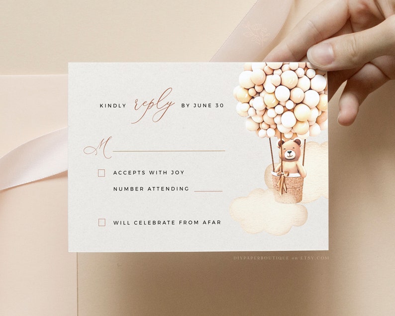May include: A white RSVP card with a brown teddy bear in a hot air balloon made of beige and white balloons. The card has the text "KINDLY reply BY JUNE 30" and two checkboxes: "ACCEPTS WITH JOY" and "WILL CELEBRATE FROM AFAR".