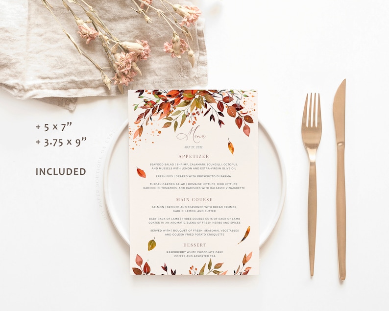 May include: A fall-themed wedding menu card with watercolor leaves in shades of orange, red, and yellow. The menu includes appetizer, main course, and dessert options. The text on the card reads "Menu" and "July 27, 2022".
