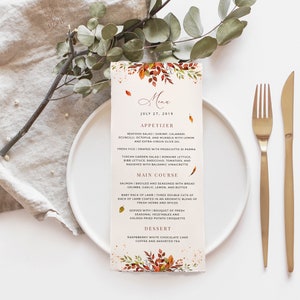May include: A printable wedding menu card with a watercolor floral design in shades of orange, red, and yellow. The menu features a seafood salad appetizer, salmon main course, and a raspberry white chocolate cake dessert. The text reads "Menu" and "July 27, 2019".