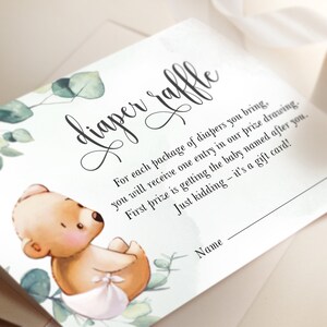 May include: A white card with green foliage and a cute cartoon bear wearing a diaper. The card says "diaper raffle" and has text explaining the rules of the raffle. The text says "For each package of diapers you bring, you will receive one entry in our prize drawing. First prize is getting the baby named after you. Just kidding - it's a gift card!" There is a line for the participant to write their name.