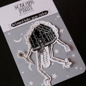 K&ouml;nnte beinhalten: Schwarz-wei&szlig;er Sticker einer hausartigen Figur mit langen Beinen und einem L&ouml;wenzahnpfennig. Die Figur befindet sich auf einem grauen Hintergrund mit wei&szlig;en Sternen und Monden. Der Sticker lautet "botanical baba yaga sticker".