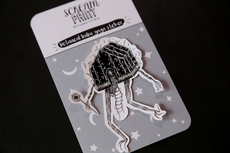 K&ouml;nnte beinhalten: Schwarz-wei&szlig;er Sticker einer hausartigen Figur mit langen Beinen und einem L&ouml;wenzahnpfennig. Die Figur befindet sich auf einem grauen Hintergrund mit wei&szlig;en Sternen und Monden. Der Sticker lautet "botanical baba yaga sticker".