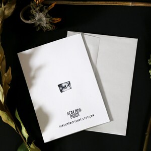 May include: A white card with a black and white illustration of an envelope with a heart on it. The card has the text "Scream Print" and "screamprintshop.etsy.com" printed on it.