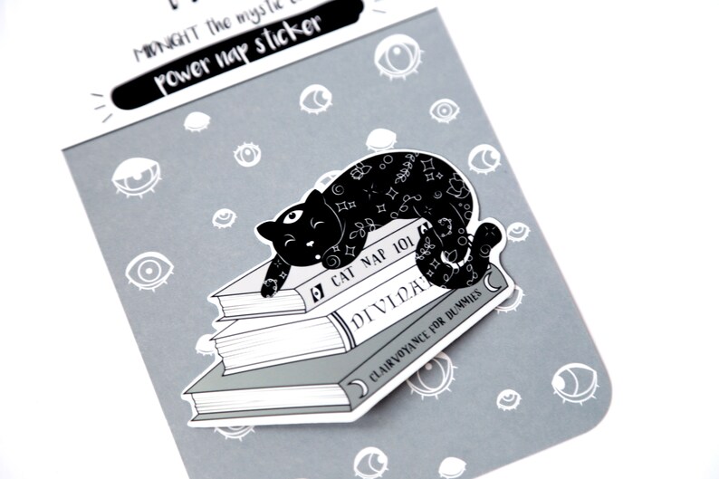 Puede incluir: Ilustraci&oacute;n en blanco y negro de un gato durmiendo sobre una pila de libros. Los libros se titulan "Cat Nap 101", "Divid" y "Clairvoyance for Dummies".