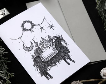 May include: A black and white illustration of a goat with a wreath, stars, a crescent moon, and a small house hanging from a string. The goat is standing on a snowy ground with a pine tree in the background.